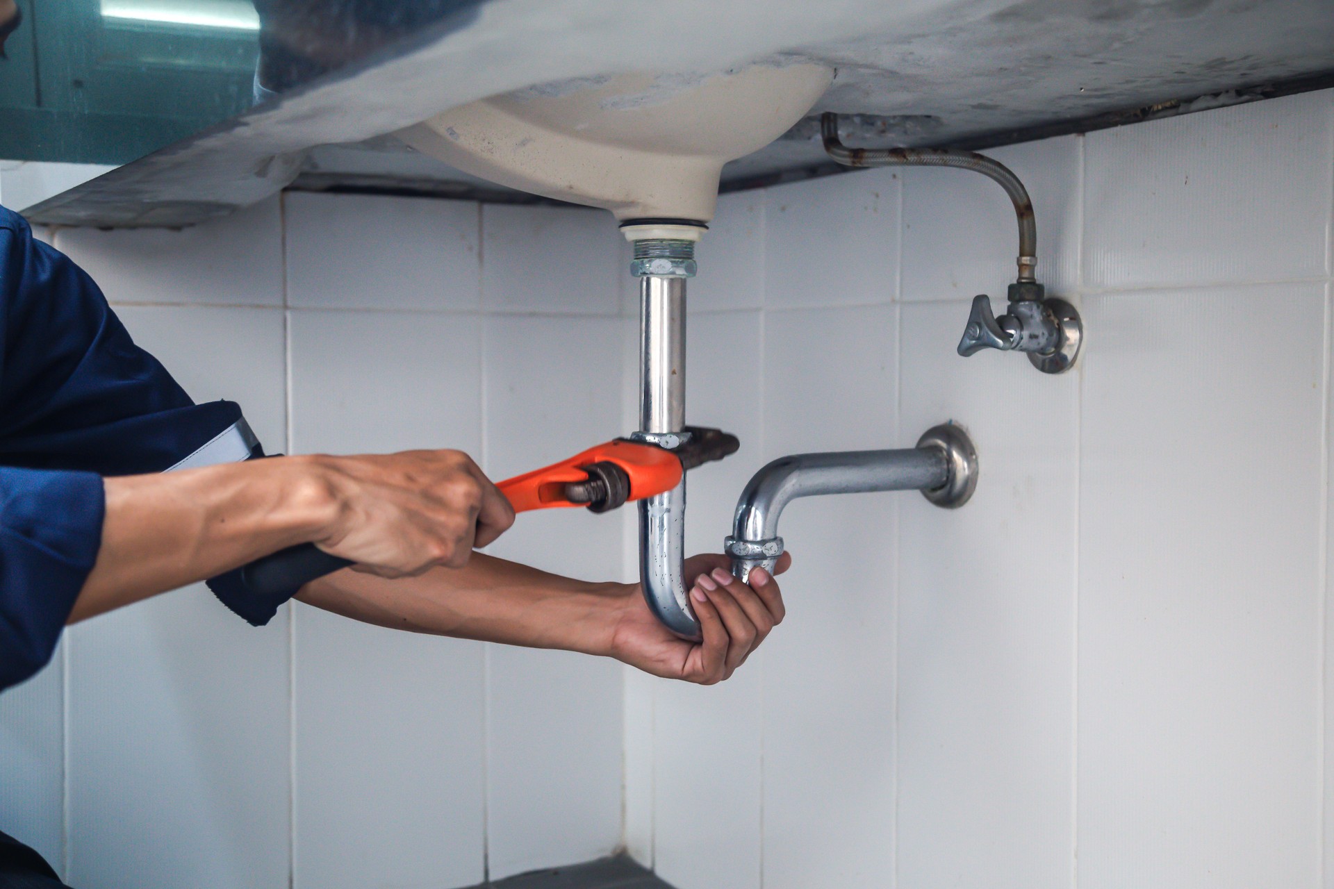 Plombier travaillant dans la salle de bains, service de réparation de plomberie, réparant des éviers de fuite avec la clé réglable, assemblent et installent le concept.